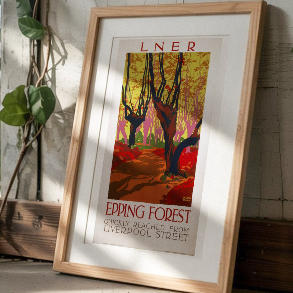 Framed epping forest artwork on a concrete floor with plants and a blurred indoor background